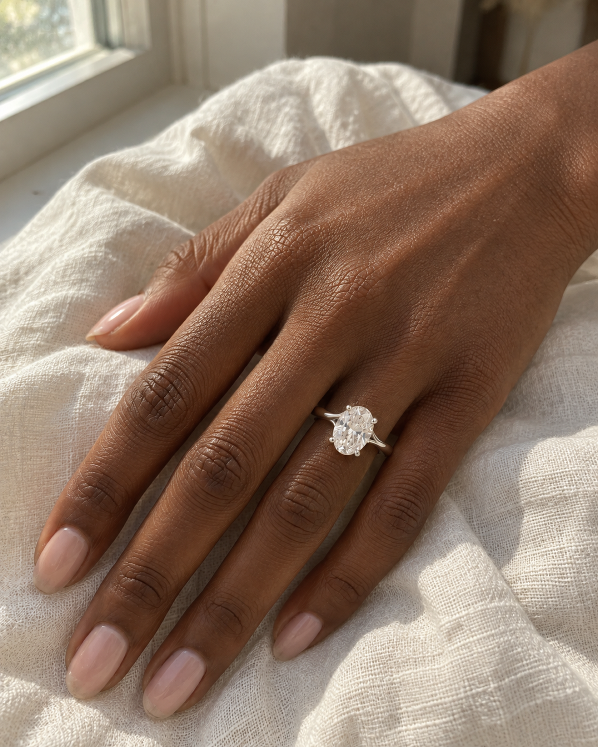 Éclat oval ring worn by a Black woman beside a window